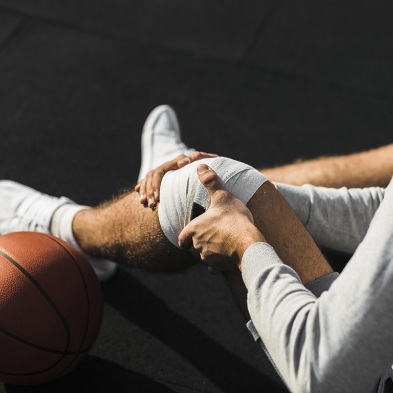 basketball-player-applying-bandage-knee
